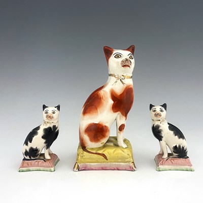 Lot 1036 - Three Staffordshire pottery cats, 19th century,...