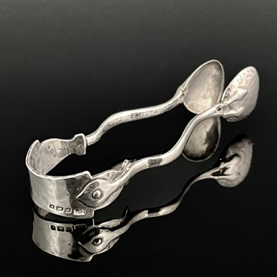 Lot 201 - A pair of Arts and Crafts silver sugar tongs,...