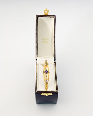 Lot 3 - An early 20th century 9ct gold amethyst and pearl bangle bracelet