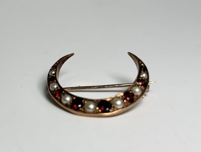 Lot 273 - A 9ct gold garnet and split pearl crescent brooch