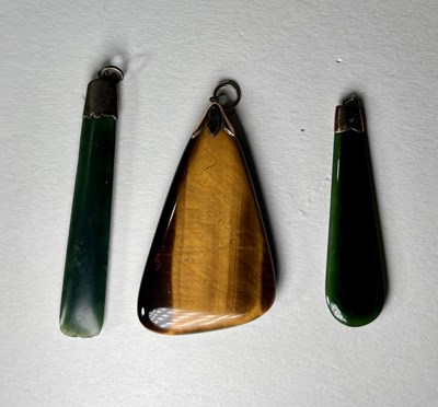 Lot 678 - Three early to mid 20th century nephrite jade and tiger's-eye pendants, with yellow metal caps