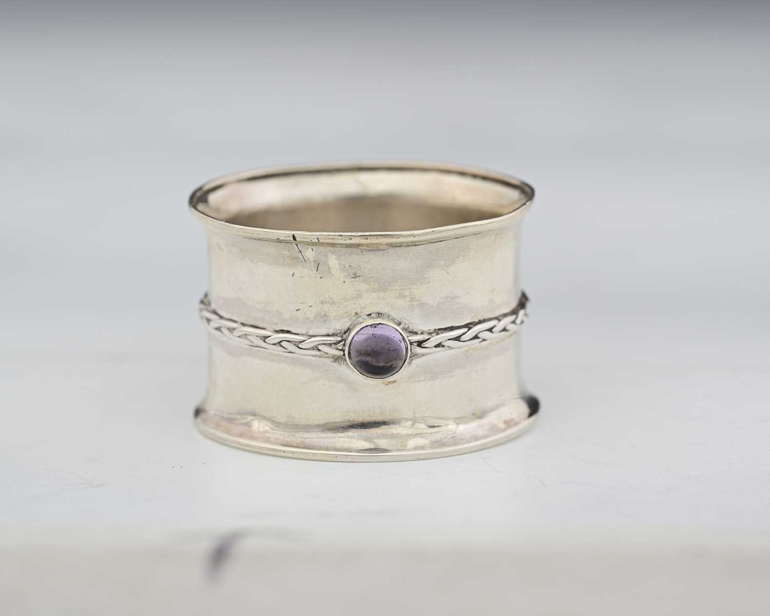 Lot 55 - An Arts and Crafts silver and gem set napkin...