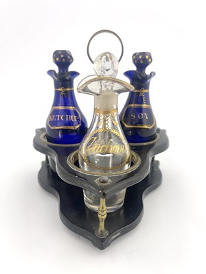 Lot 480 - A George III three bottle glass cruet in wooden stand